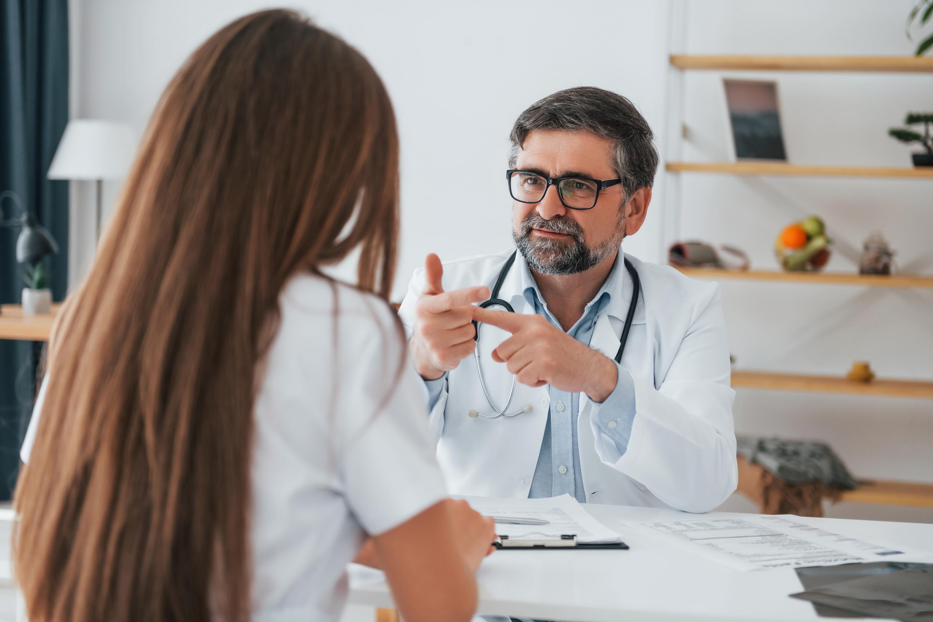 Femme qui montre à son médecin des squames visage causes par une dermite séborrhéique